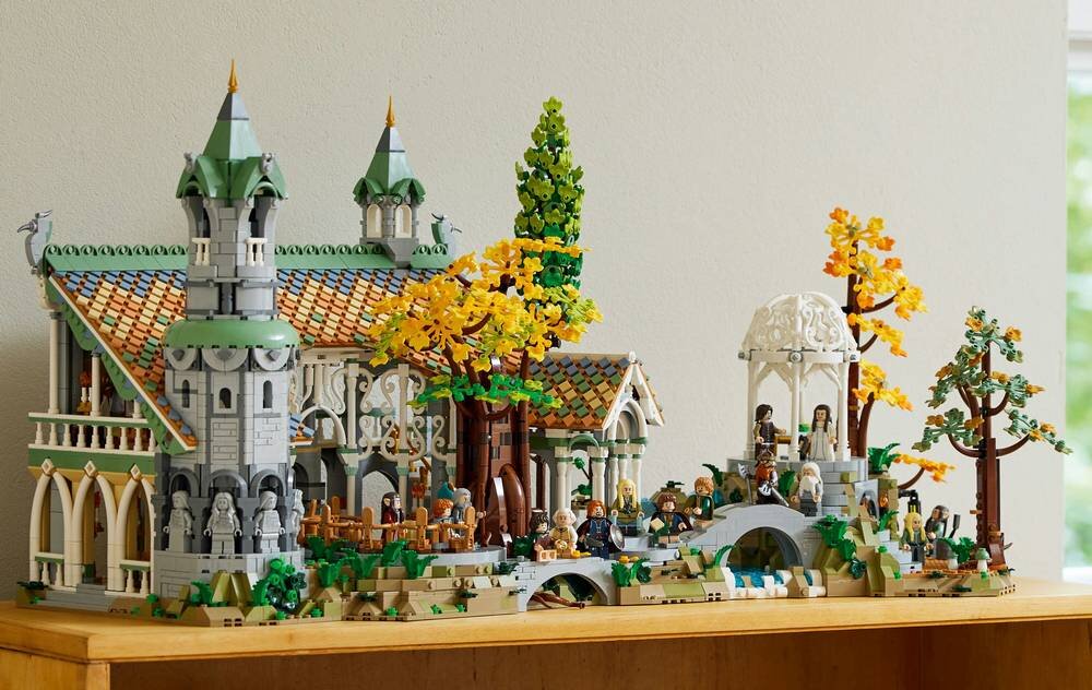Zestaw LEGO przedstawiający szczegółowy model Rivendell z Władcy Pierścieni, z widocznymi budynkami, drzewami i postaciami. Konstrukcja jest bogata w detale architektoniczne i kolorowe elementy roślinne.