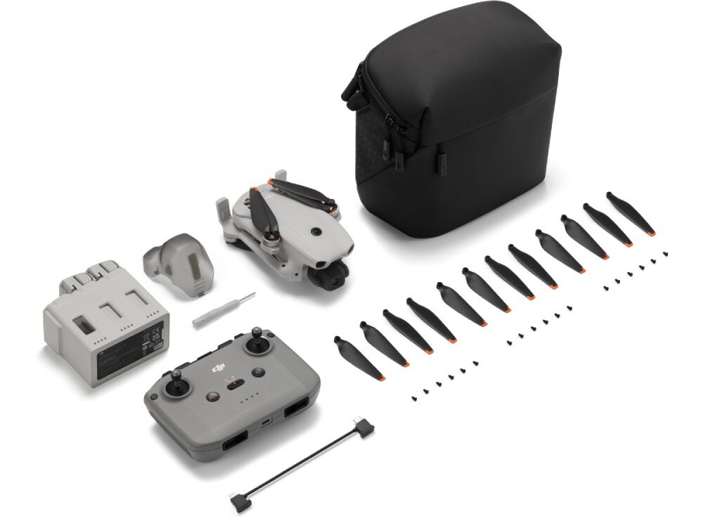 Dron DJI Lito 1 Na białym tle rozłożone są elementy zestawu drona: szary dron ze złożonymi śmigłami, cztery zapasowe czarne śmigła, szary pilot zdalnego sterowania, śrubokręt, zapasowe śruby, kabel USB, instrukcja obsługi i osłona gimbala
