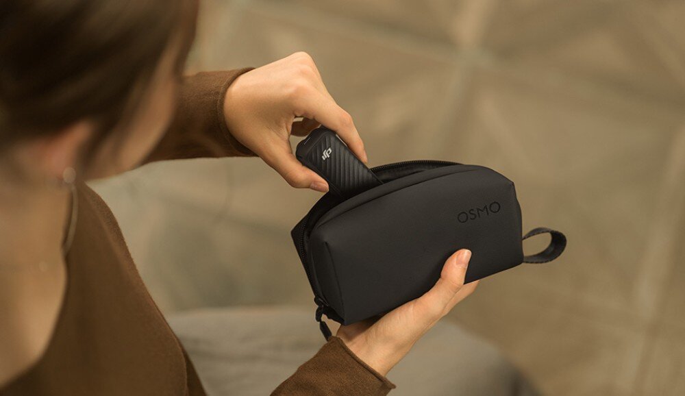 Kamera sportowa DJI OSMO POCKET 4 dłoń wkładająca urządzenie z kamerą do małego, czarnego etui z napisem osmo, druga dłoń trzyma etui