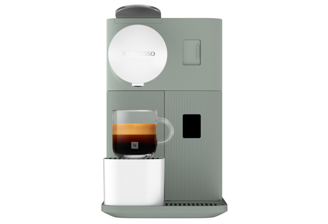 Szary ekspres do kawy z logo \'Nespresso\' na okrągłym elemencie. Na ekspresie stoi szklanka z kawą z pianką.
