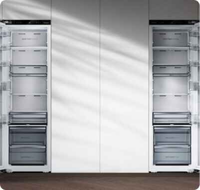 Obraz przedstawia dwie otwarte lodówki z kilkoma szufladami i półkami. Wnętrza są puste, a drzwi lodówek mają przezroczyste półki.