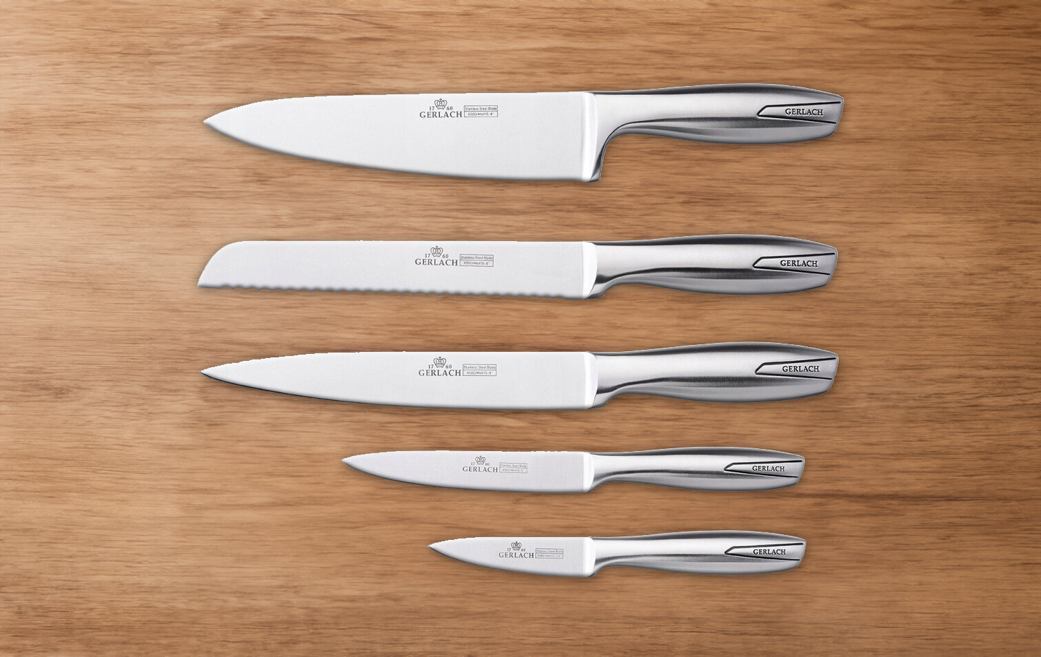 Na drewnianej powierzchni leży pięć noży kuchennych o metalowych rękojeściach. Na ostrzach widoczne jest logo \'GERLACH\'.