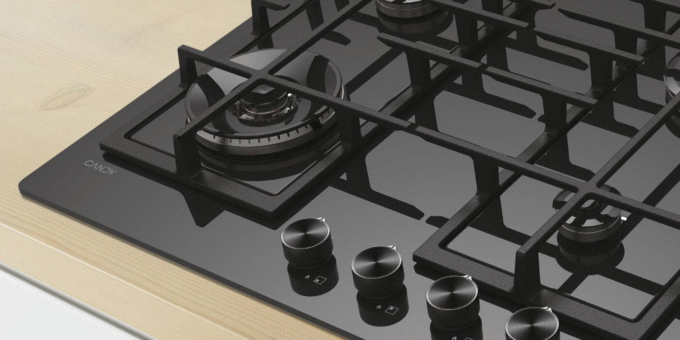 Czarna płyta gazowa z czterema palnikami i metalowymi pokrętłami. Na powierzchni widoczne jest logo \'CANDY\'.