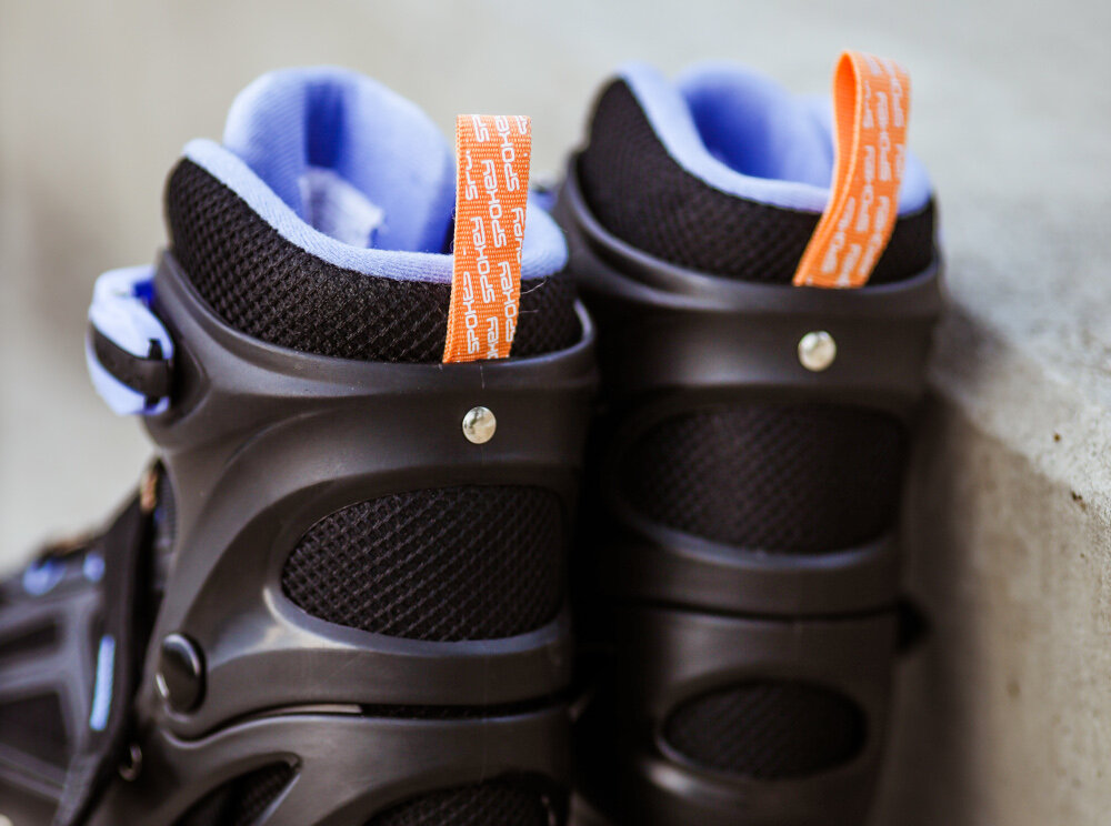 Czarno-fioletowe łyżworolki z pomarańczowymi uchwytami z napisem \'nao\'.