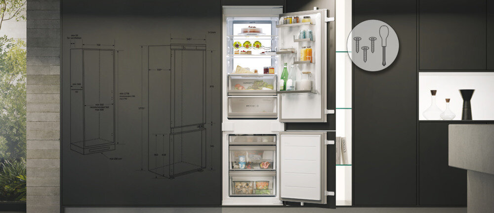 Otwarta lodówka z widocznymi półkami i produktami spożywczymi, obok rysunek techniczny lodówki na ścianie. Na drzwiach lodówki znajdują się butelki i pojemniki, a wewnątrz widoczne są różne produkty spożywcze.