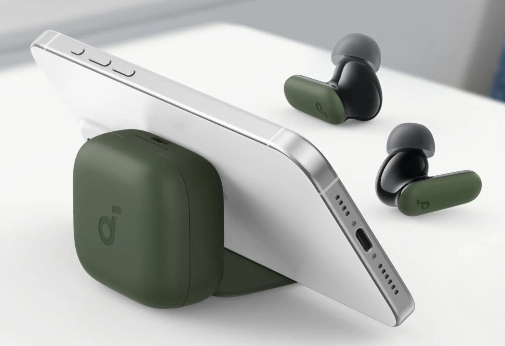 Na białej powierzchni leży smartfon oparty o zielone etui, obok znajdują się zielone słuchawki dokanałowe. Na etui widoczne jest logo w kształcie litery \'d\'.