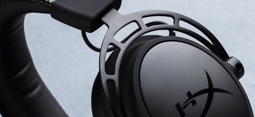 Zbliżenie na czarną nauszną słuchawkę z widocznym logo \'HYPERX\'. Słuchawka ma metalowy pałąk i miękką poduszkę nauszników.