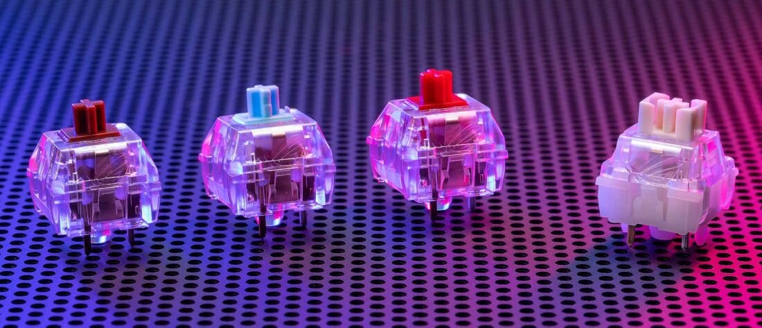 Na perforowanej powierzchni znajdują się cztery przełączniki mechaniczne w przezroczystych obudowach, z różnymi kolorami trzpieni: czerwonym, niebieskim i białym. Tło jest oświetlone gradientem kolorów od niebieskiego do różowego.