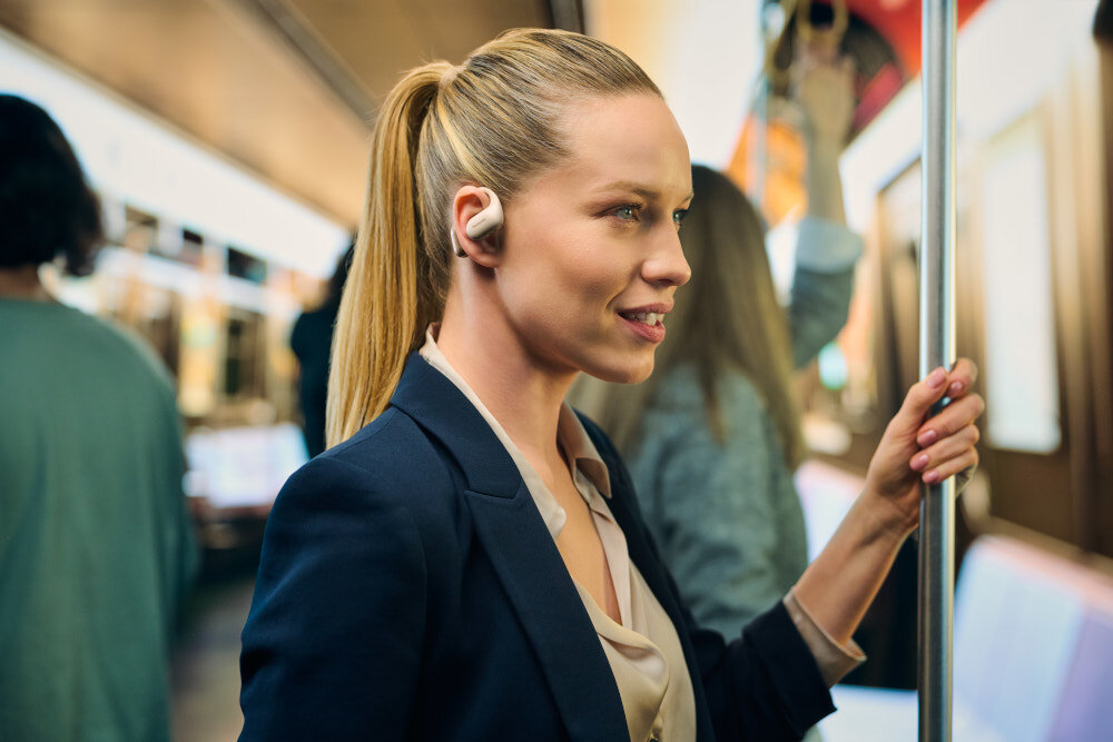 Słuchawki powietrzne PANASONIC RB-F10 - Czyste rozmowy bez zakłóceń, dwa mikrofony, redukcja hałasu w tle, osoba z założonymi słuchawkami powietrznymi w metrze