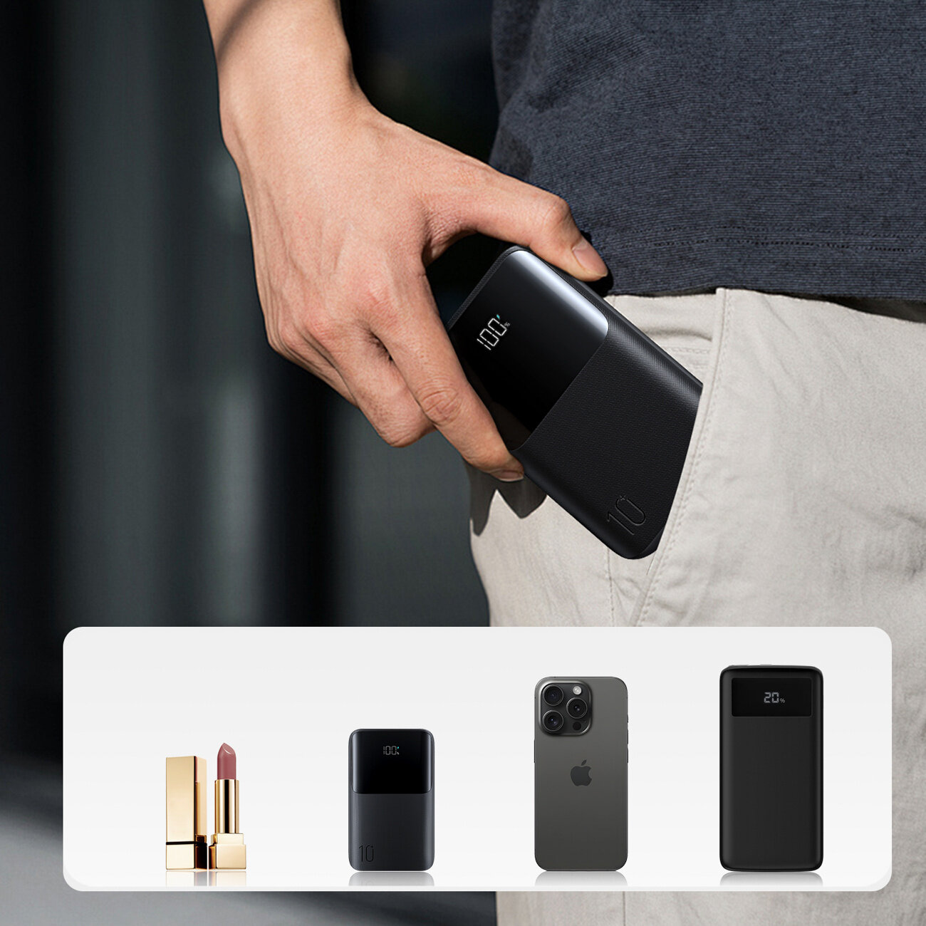 Osoba wkłada czarny powerbank z wyświetlaczem pokazującym \'100%\' do kieszeni jasnych spodni. Na dole obrazu widoczne są trzy przedmioty: szminka, powerbank oraz smartfon z logo jabłka.