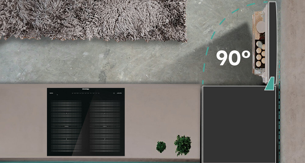 Widok z góry na otwartą lodówkę z napisem \'90°\' obok drzwi. Na podłodze widoczny jest dywan oraz dwie rośliny w doniczkach.