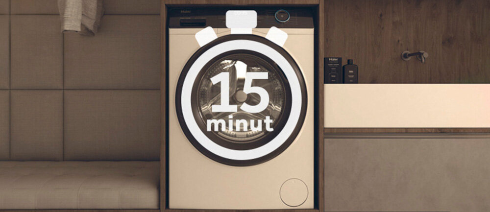 Pralka z widocznym bębnem, na którym znajduje się grafika przedstawiająca stoper z napisem \'15 minut\'. Obok pralki znajduje się szafka z umywalką i kosmetykami.