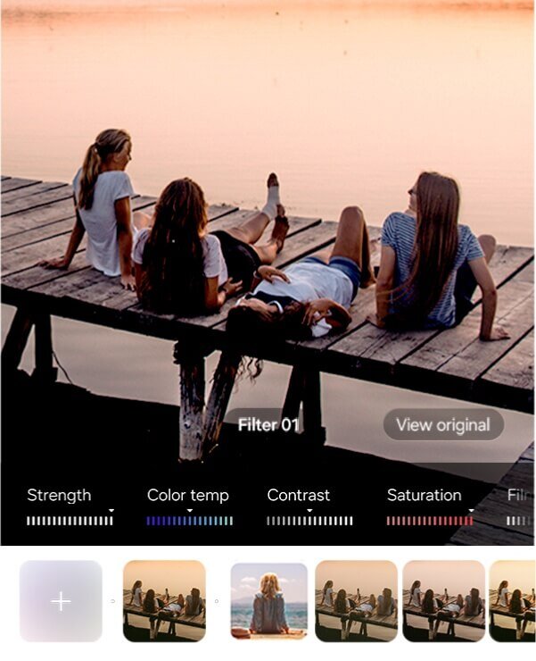 Cztery osoby siedzą na drewnianym pomoście nad wodą o zachodzie słońca. Na dole ekranu widoczne są suwaki z opcjami edycji zdjęcia: Strength, Color temp, Contrast, Saturation oraz miniatury filtrów z podpisem \'Filter 01\' i przyciskiem \'View original\'.