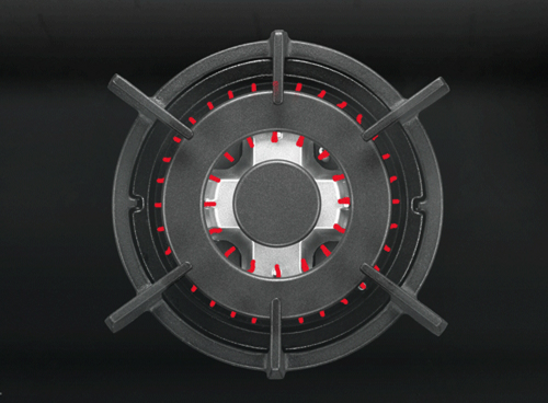 Obraz przedstawia palnik gazowy z metalowymi rusztami i czerwonymi elementami wokół centralnej części. Tło jest ciemne, co podkreśla kontrast palnika.