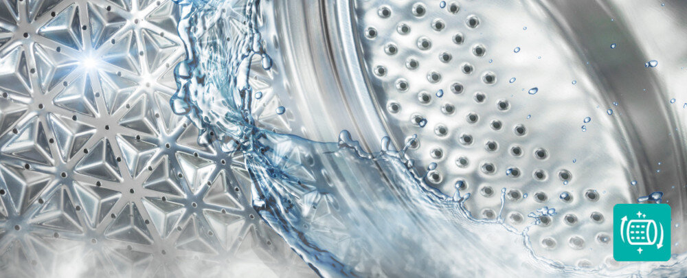 Obraz przedstawia wnętrze bębna pralki z widocznymi otworami i wzorem w kształcie gwiazdek. Na powierzchni bębna widać rozpryskującą się wodę.