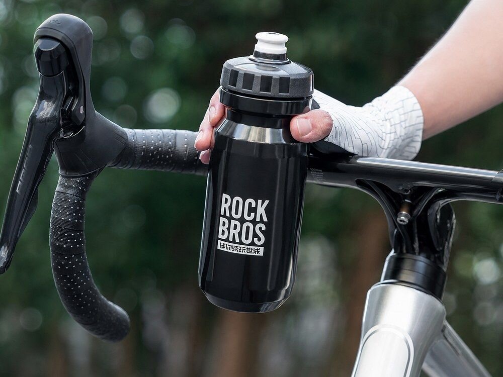 Bidon ROCKBROS 35210066001 600 ml Czarny, szczelność, uszczelka, kurz, osłona, Ręka trzymająca otwartą butelkę.