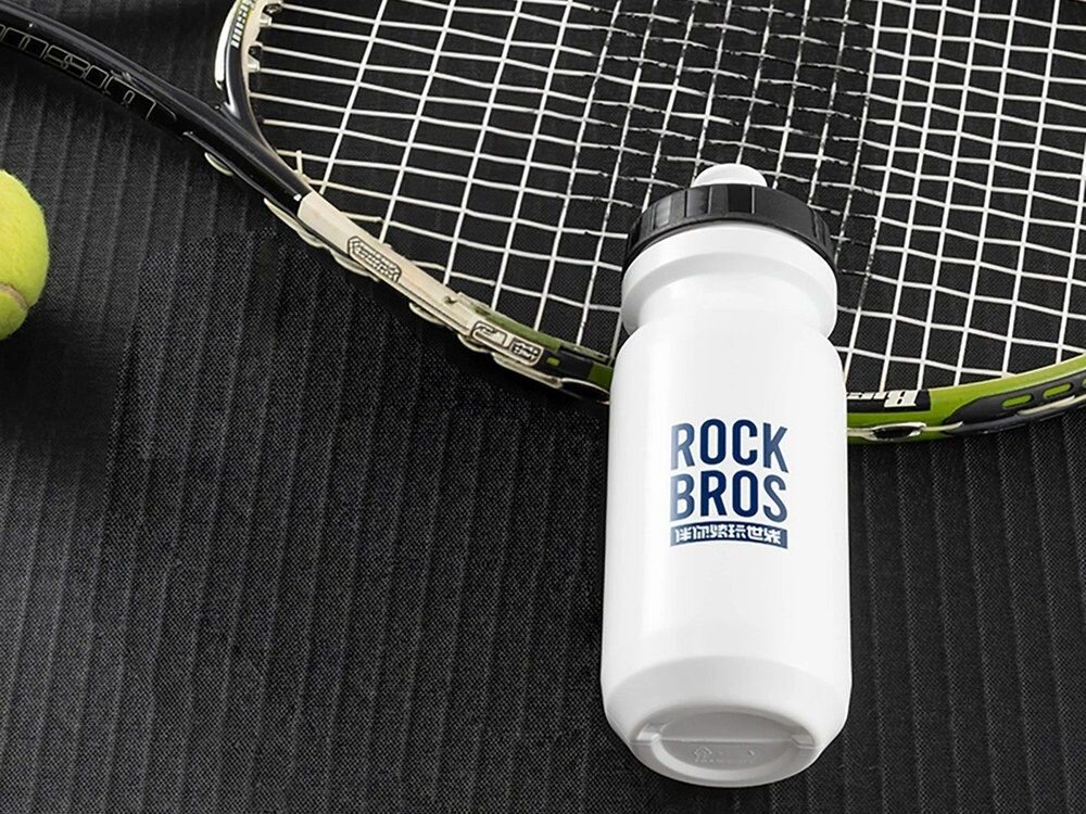 Bidon ROCKBROS 35210066004 600 ml Biały, picie, woda, sport, trasa, Bidon leżący obok rakiety tenisowej.