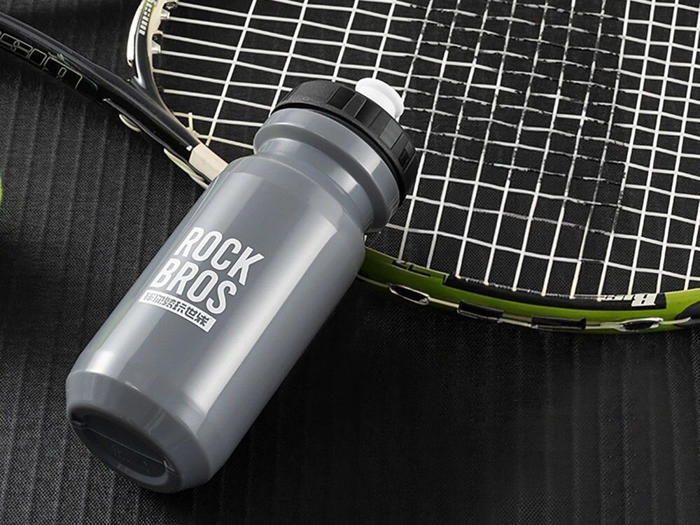 Bidon ROCKBROS 35210066005 600 ml Szary, picie, woda, sport, trasa, Bidon leżący obok rakiety tenisowej.