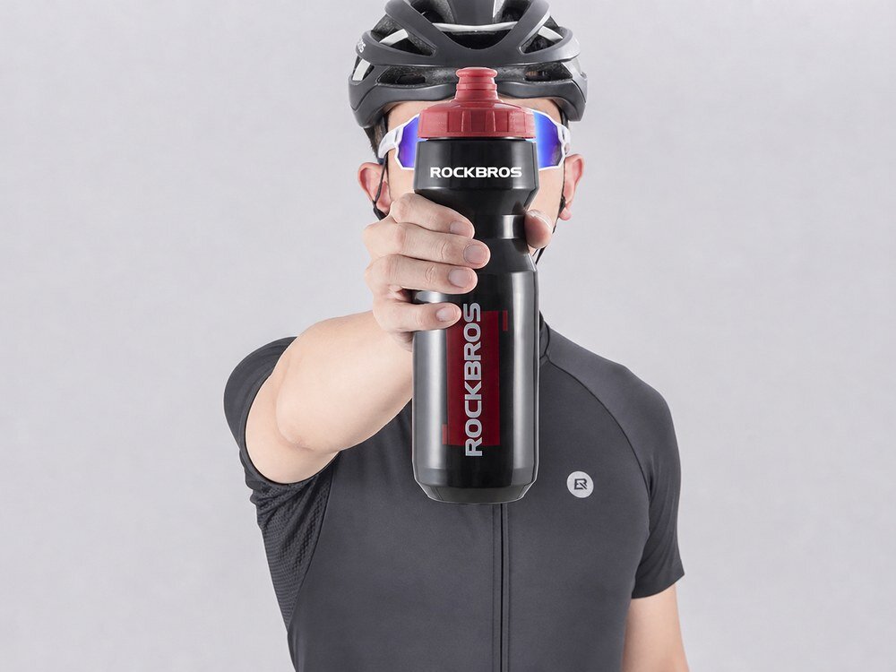 Bidon ROCKBROS DCBT69BR 750 ml Czarno-czerwony, chwyt, ergonomia, lekkość, dłoń, Rowerzysta trzymający butelkę przed sobą.