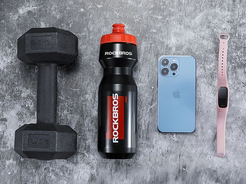 Bidon ROCKBROS DCBT69BR 750 ml Czarno-czerwony, polipropylen, wytrzymałość, korek, smak, Butelka obok hantla, telefonu i zegarka.