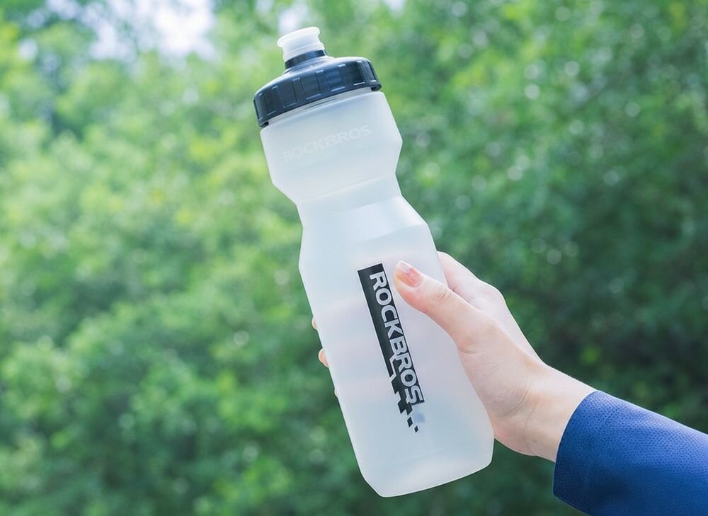 Bidon ROCKBROS DCBT69TBK 750 ml Przezroczysto-czarny, chwyt, ergonomia, lekkość, dłoń, Rowerzysta trzymający butelkę przed sobą.