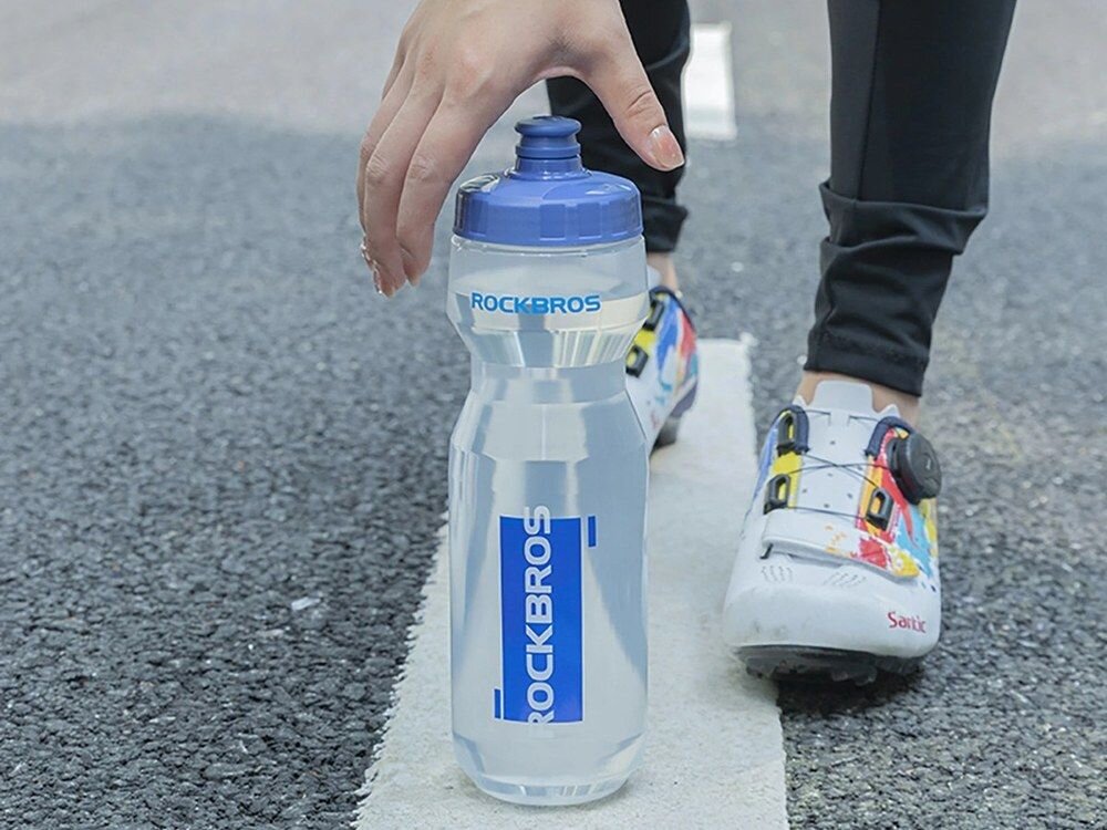 Bidon ROCKBROS DCBT69TB 750 ml Przezroczysto-niebieski, chwyt, ergonomia, lekkość, dłoń, Rowerzysta trzymający butelkę przed sobą.
