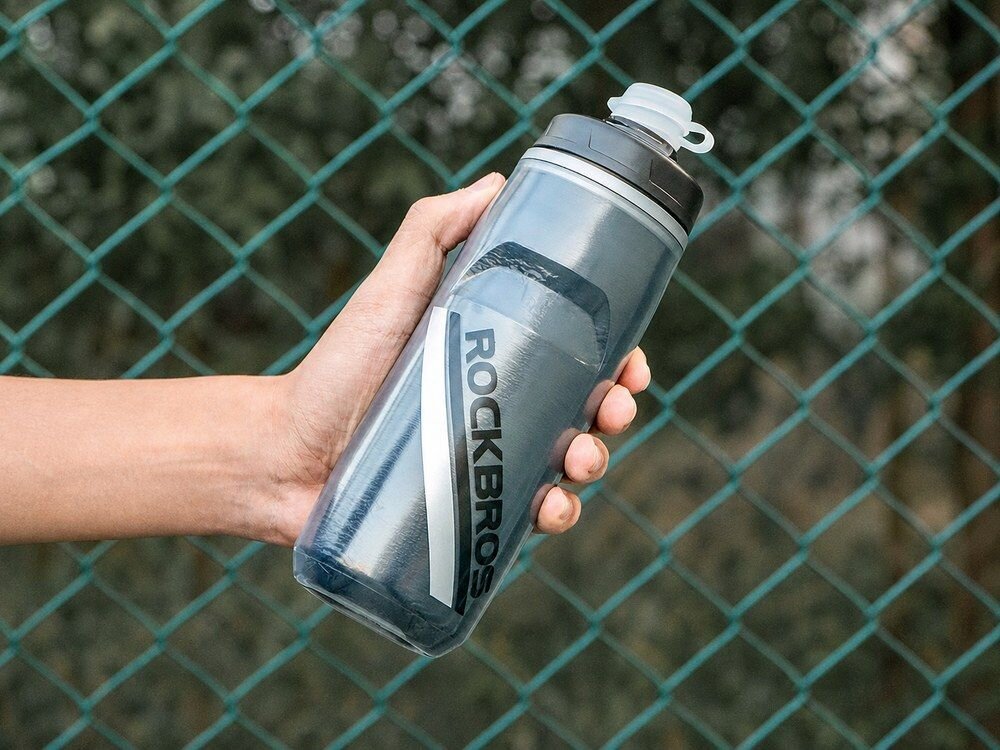 Bidon ROCKBROS 35210022002 620 ml Czarny, design, logo, sportowy, sylwetka, Dłoń trzymająca bidon na tle siatki.