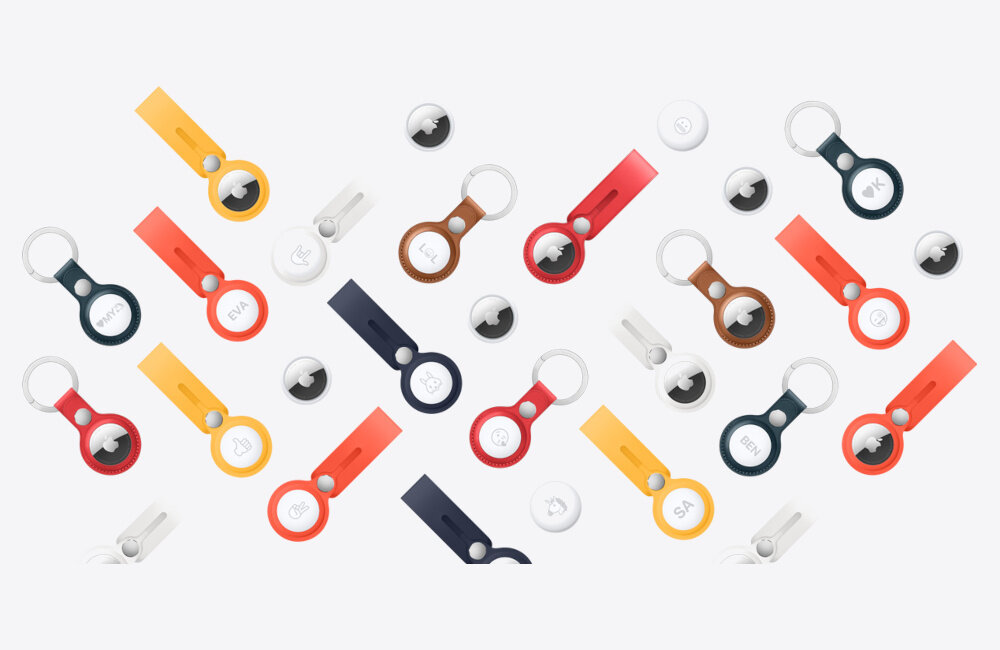 Na obrazie widoczne są różnokolorowe breloki z okrągłymi urządzeniami, które mogą być lokalizatorami. Urządzenia mają gładką, błyszczącą powierzchnię z logo w kształcie nadgryzionego jabłka.