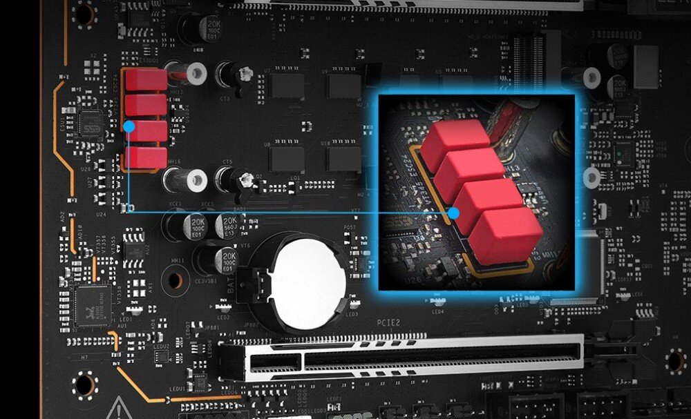 Zdjęcie przedstawia fragment płyty głównej z widocznymi elementami elektronicznymi, w tym czerwonymi komponentami. W centralnej części znajduje się powiększenie jednego z obszarów z trzema czerwonymi elementami.