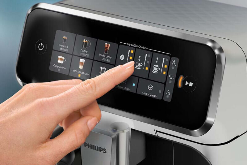 Zbliżenie na panel dotykowy ekspresu do kawy z widocznymi ikonami napojów, takimi jak Espresso, Coffee, Iced Coffee, Cappuccino i Latte Macchiato. Logo PHILIPS znajduje się poniżej panelu.