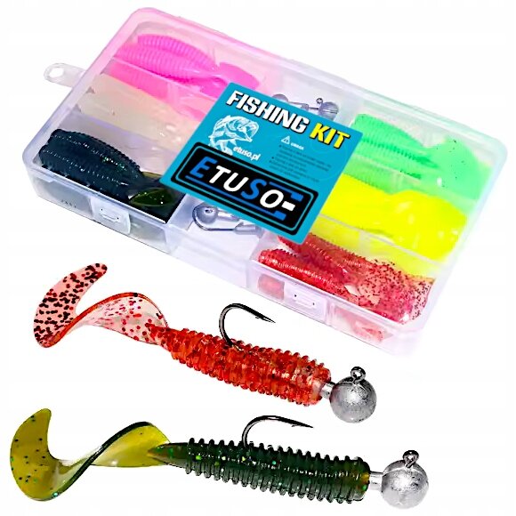 Na obrazie widoczny jest zestaw przynęt spinningowych w plastikowym pudełku z napisem \'FISHING KIT ETUSO\'. Przed pudełkiem znajdują się dwie gumowe przynęty z główkami jigowymi w kolorach czerwonym i zielonym.