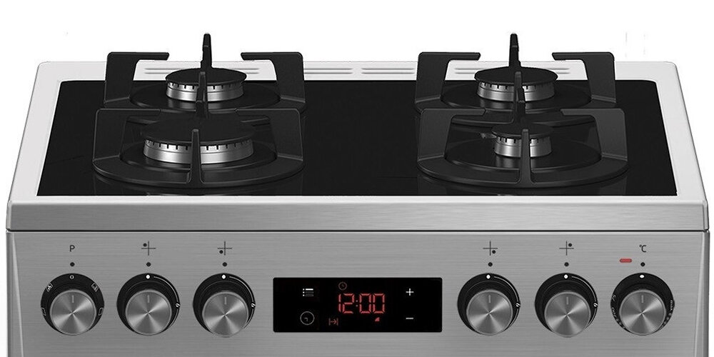 Kuchnia gazowa z czterema palnikami na górze i panelem sterowania z pokrętłami oraz wyświetlaczem cyfrowym pokazującym godzinę 12:00. Panel wykonany ze stali nierdzewnej z czarnymi elementami.