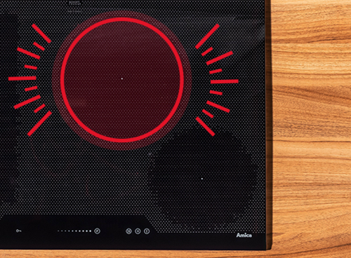 Czarna płyta grzewcza z czerwonymi oznaczeniami wskazującymi aktywne pole grzewcze. Widoczne logo \'Amica\' w dolnym rogu.