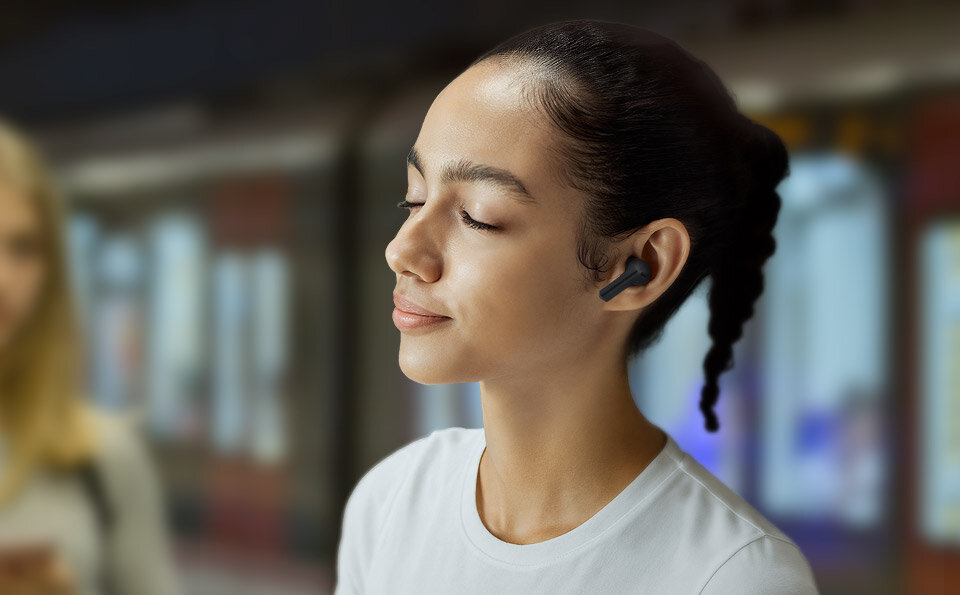 Kobieta z słuchawkami Black Galaxy Buds3 FE w miejskim otoczeniu.