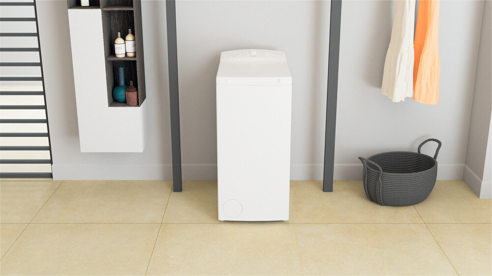 Na obrazie znajduje się biała pralka ładowana od góry, ustawiona w jasnym pomieszczeniu. Obok pralki widoczne są półki z kosmetykami oraz kosz na pranie.