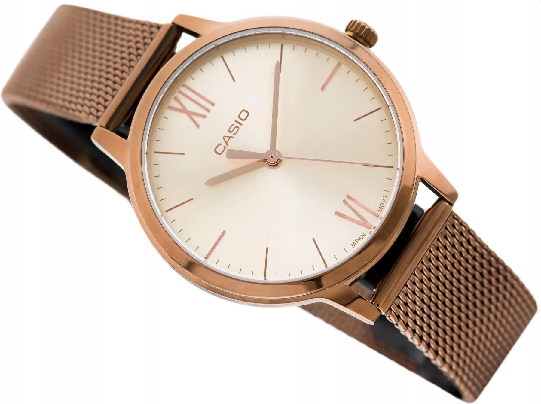 Zegarek z okrągłą tarczą w kolorze różowego złota, z logo \'CASIO\' na środku. Bransoleta ma siatkowy wzór, a na tarczy widoczne są rzymskie cyfry XII i VI.