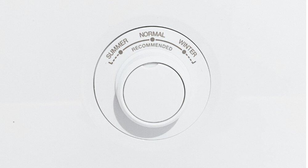 Obraz przedstawia biały panel z pokrętłem, na którym widoczne są napisy: \'SUMMER\', \'NORMAL\', \'WINTER\' oraz \'RECOMMENDED\'.