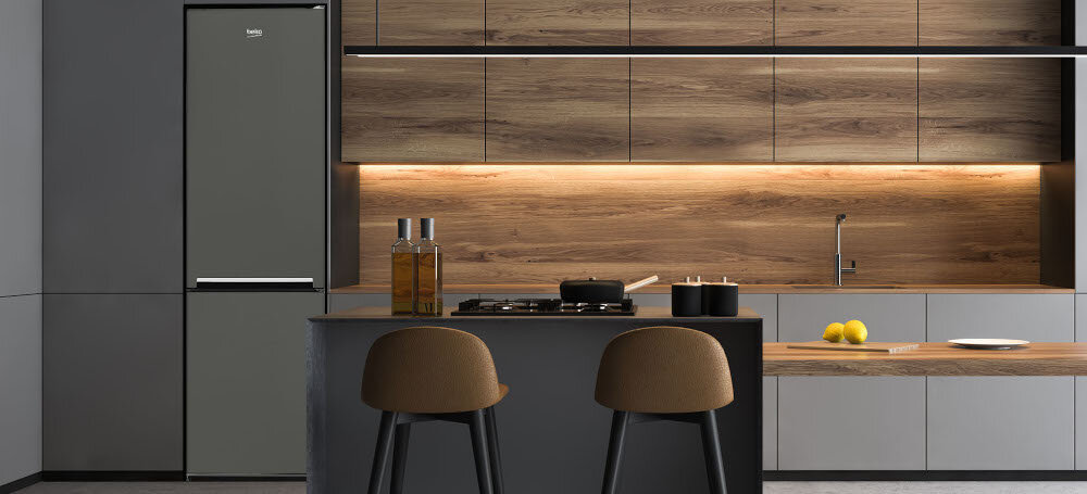 Kuchnia z nowoczesnym wystrojem, w której znajduje się grafitowa lodówka z logo \'beko\'. Na wyspie kuchennej stoją dwa krzesła, a na blacie widoczne są garnki i cytryny.