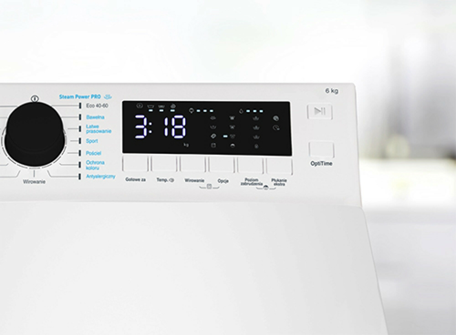 Panel sterowania pralki z wyświetlaczem pokazującym czas 3:18 oraz różnymi przyciskami i pokrętłem do wyboru programów. Widoczne są napisy takie jak \'Steam Power Pro\', \'6 kg\', \'OptiTime\' oraz różne programy prania.
