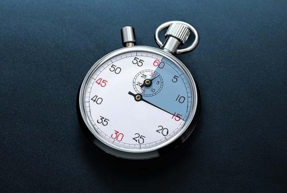 Na obrazie widoczny jest stoper z białą tarczą i czarnymi oraz czerwonymi oznaczeniami liczbowymi. Stoper leży na ciemnym tle.