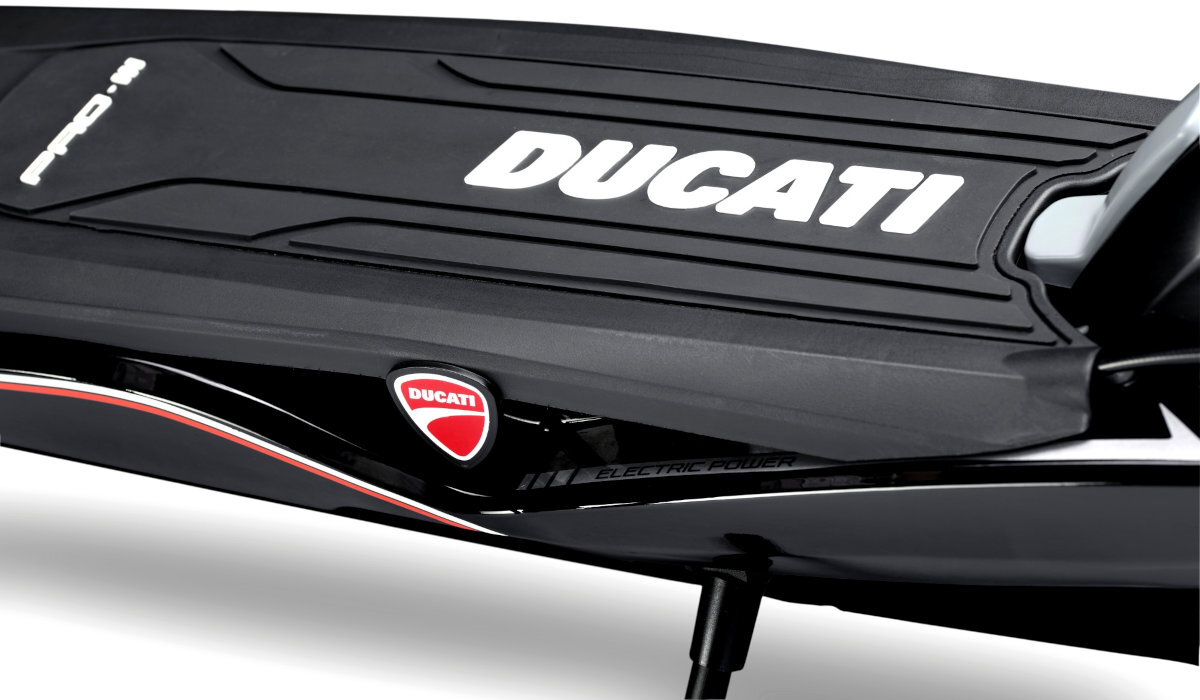 Czarna hulajnoga elektryczna z widocznym logo \'DUCATI\' na platformie. Na boku znajduje się czerwono-białe logo \'DUCATI\' oraz napis \'ELECTRIC POWER\'.