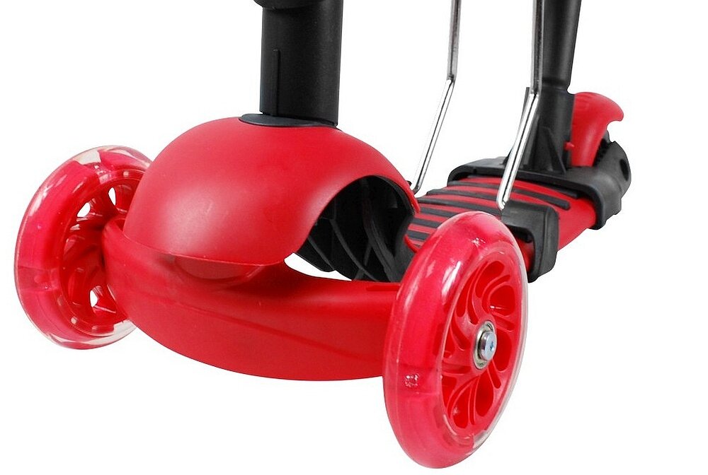 Czerwona hulajnoga dziecięca z trzema kołami, z czego dwa są z przodu i jedno z tyłu. Posiada czarną platformę z czerwonymi akcentami oraz metalowe elementy konstrukcyjne.