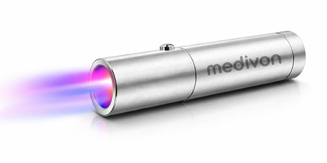 Metaliczne urządzenie cylindryczne z napisem \'medivon\' emituje kolorowe światło z jednego końca.