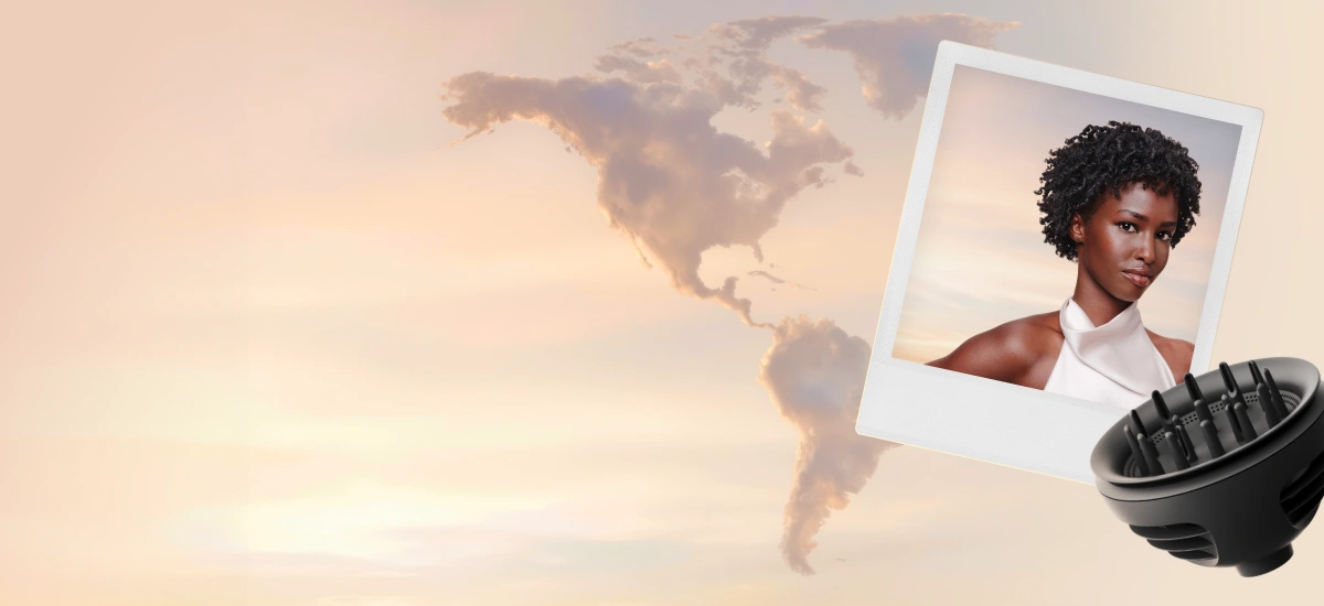 Dyfuzor leży obok zdjęcia w białej ramce z modelką z kręconymi włosami. W tle jasne niebo z chmurami w kształcie obu Ameryk.