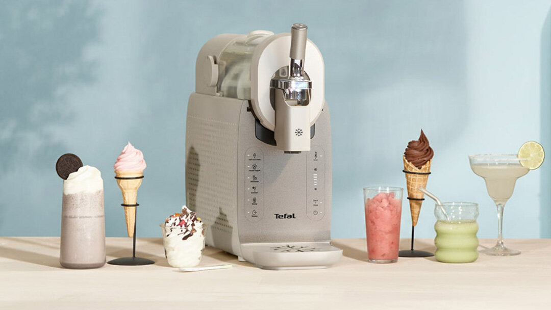Maszynka do lodów TEFAL Freezi IG803AE0 na blacie, obok różne lody i napoje.