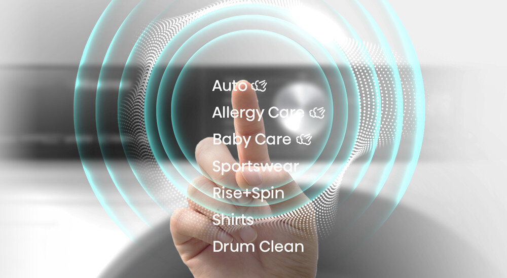 Obraz przedstawia dłoń wskazującą na ekran z listą programów pralki: Auto, Allergy Care, Baby Care, Sportswear, Rise+Spin, Shirts, Drum Clean. W tle widoczne są koncentryczne kręgi świetlne.