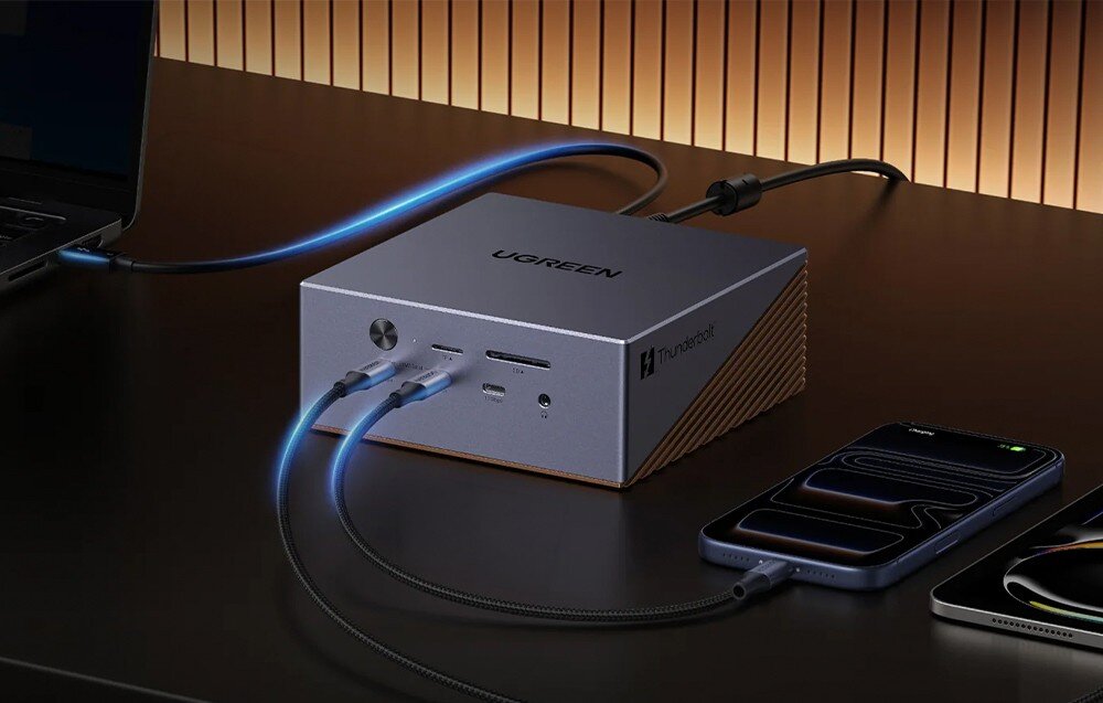 Na obrazie widoczna jest stacja dokująca z napisem \'UGREEN\' oraz logo \'Thunderbolt\', do której podłączone są różne urządzenia za pomocą kabli. W tle znajduje się ściana z pionowymi, drewnianymi panelami.