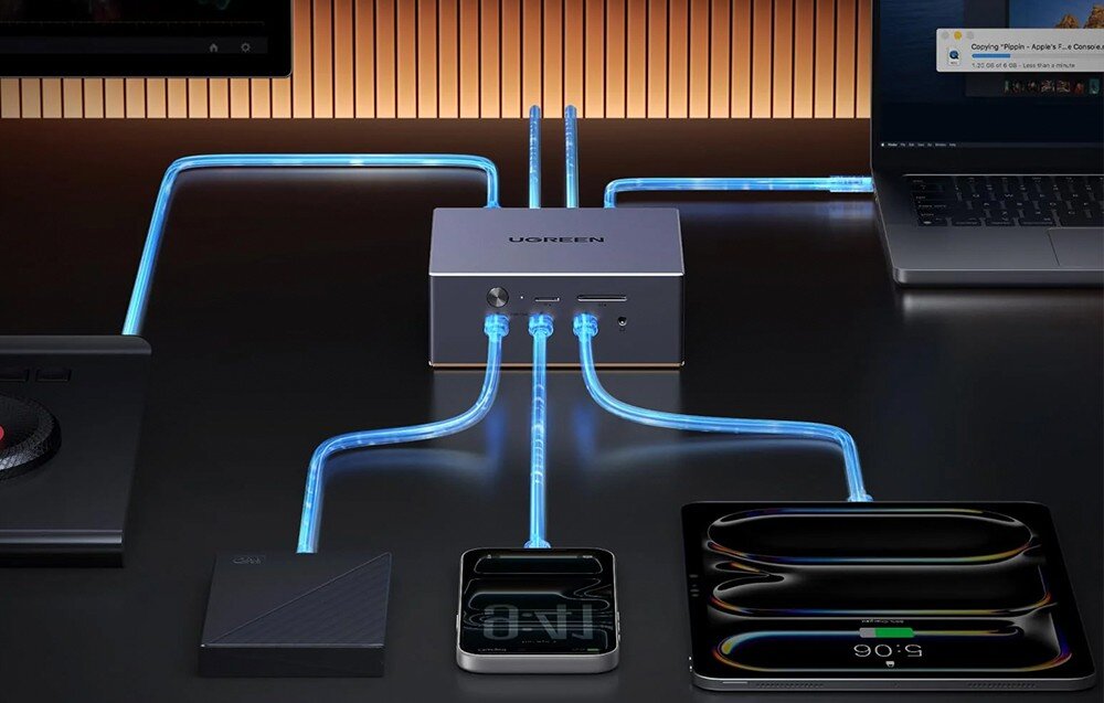 Na obrazie widoczna jest stacja dokująca z logo UGREEN, do której podłączone są różne urządzenia za pomocą świecących kabli. W tle znajduje się drewniana ściana z pionowymi liniami.
