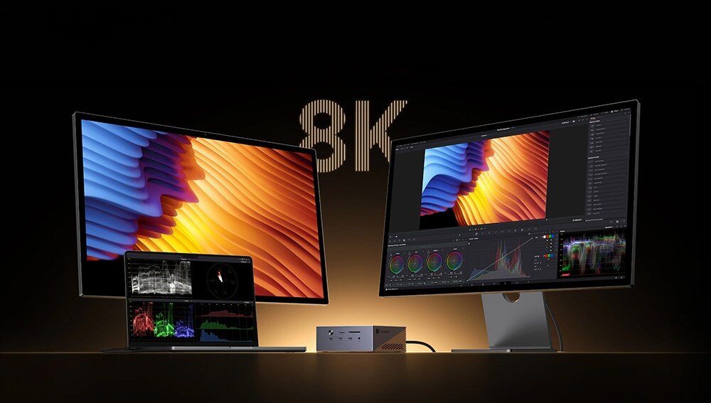 Obraz przedstawia dwa monitory z wyświetlanymi kolorowymi grafikami oraz stację dokującą umieszczoną pomiędzy nimi. W tle widoczny jest napis \'8K\'.