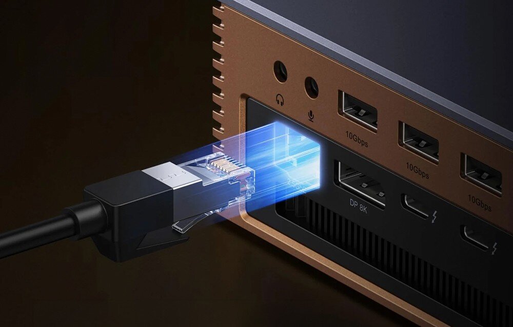 Obraz przedstawia stację dokującą z kilkoma portami, w tym portem Ethernet, do którego podłączony jest kabel sieciowy. Widoczne są również porty oznaczone jako \'10Gbps\' oraz \'DP 8K\'.